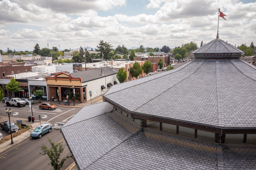 Aerial of roof of round building with tan building in the distance 