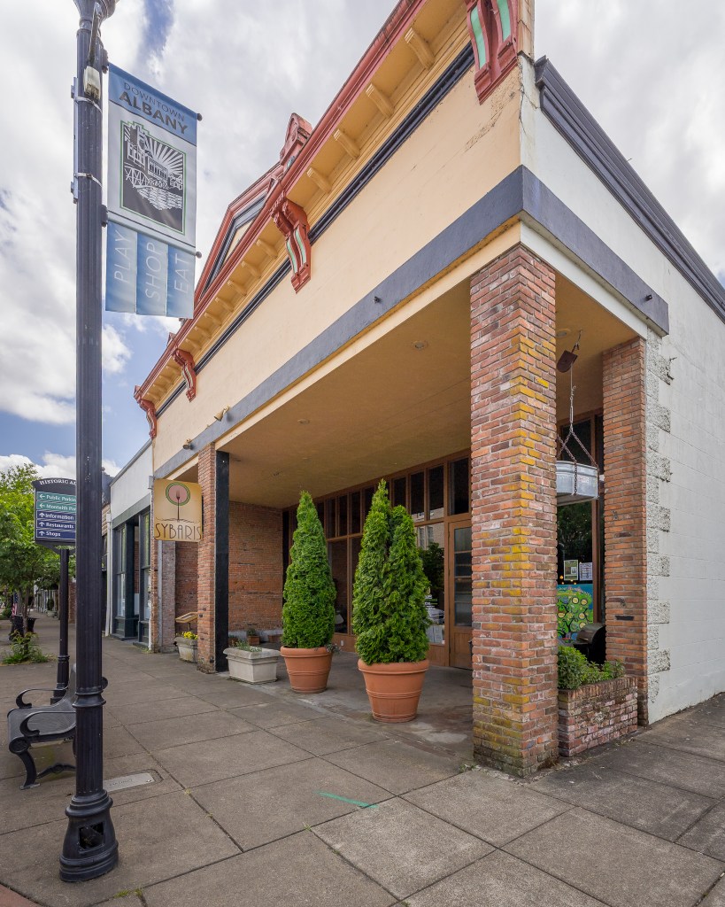 View of tree shrubs in front of dining area and downtown Albany banner on pole